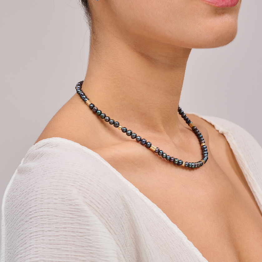 שרשרת צמודה עם פנינים שחורות ואלמנטים מוזהבים – קולר עם אמירה מסוגננת, שמשלב בין עומק אלגנטי לנגיעה חמימה של זהב. הפנינים השחורות יוצרות נוכחות דרמטית אך הרמונית, ואילו חרוזי הגולדפילד מוסיפים קונטרסט זוהר וקו עיצובי נקי אך מרשים. העיצוב הצמוד לצוואר מדגיש את קווי המתאר ומעניק מראה נשי, חזק ומתוחכם. תכשיט מתאים גם לערב וגם ליום, עם מגע של סטייל.