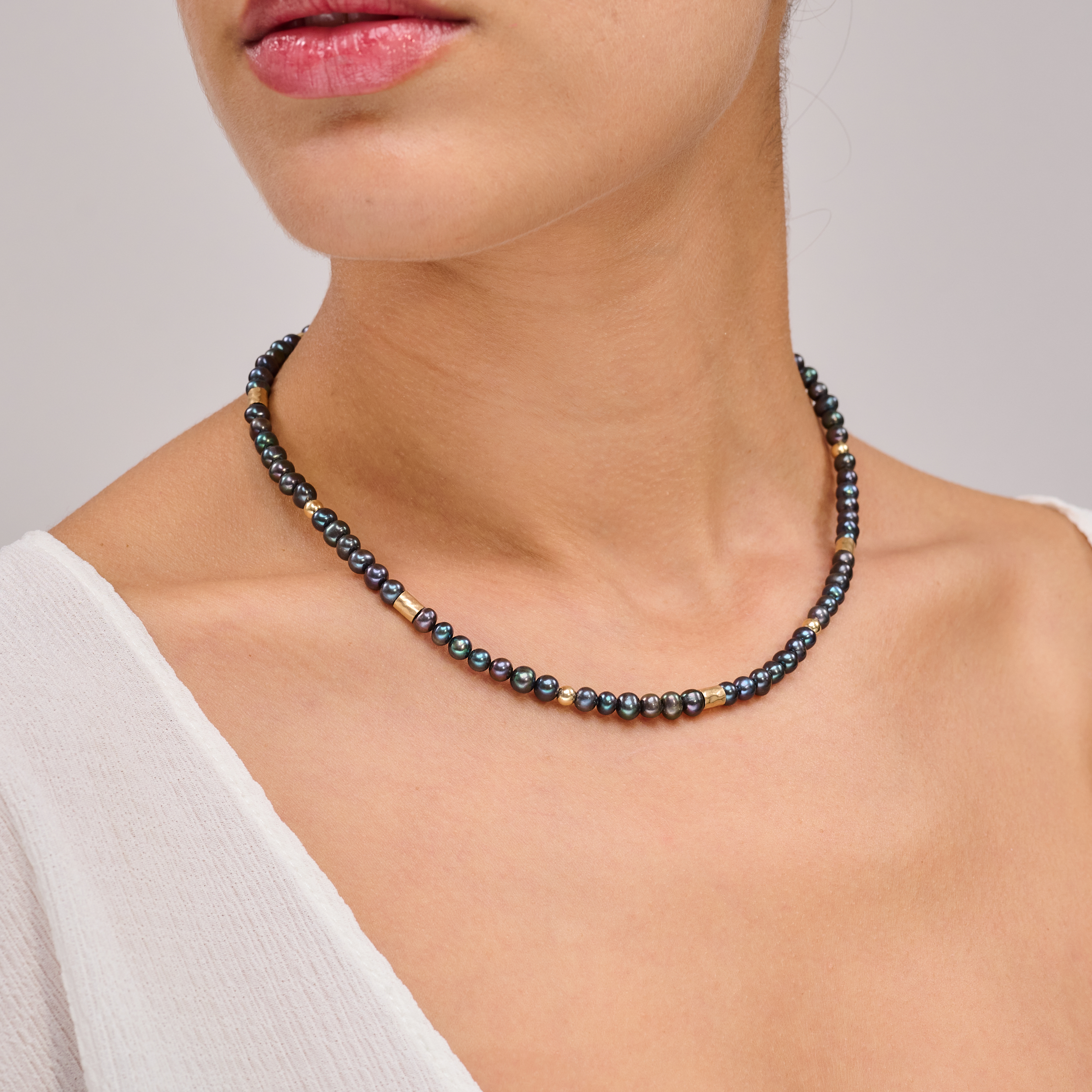 שרשרת צמודה עם פנינים שחורות ואלמנטים מוזהבים – תכשיט דרמטי עם איזון מדויק, שמשלב בין עומק אלגנטי לנגיעה חמימה של זהב. הפנינים השחורות יוצרות נוכחות דרמטית אך הרמונית, ואילו חרוזי הגולדפילד מוסיפים קונטרסט זוהר וניחוח טרנדי אלגנטי. העיצוב הצמוד לצוואר מדגיש את קווי המתאר ומעניק מראה נשי, חזק ומתוחכם. תכשיט למראה חגיגי או כטאץ’ מדויק ביומיום.
