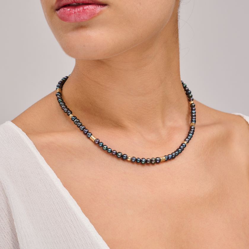 שרשרת צמודה עם פנינים שחורות ואלמנטים מוזהבים – תכשיט דרמטי עם איזון מדויק, שמשלב בין עומק אלגנטי לנגיעה חמימה של זהב. הפנינים השחורות יוצרות נוכחות דרמטית אך הרמונית, ואילו חרוזי הגולדפילד מוסיפים קונטרסט זוהר וניחוח טרנדי אלגנטי. העיצוב הצמוד לצוואר מדגיש את קווי המתאר ומעניק מראה נשי, חזק ומתוחכם. תכשיט למראה חגיגי או כטאץ’ מדויק ביומיום.