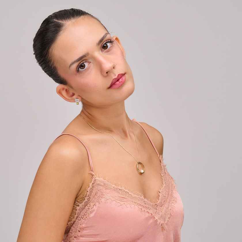 שרשרת בעיצוב אלגנטי עם אלמנט מרכזי מצופה זהב מבריק, המשובץ בפנינה לבנה קלאסית עם ברק טבעי – תכשיט קלאסי בעל נוכחות בולטת. הפנינה ממוקמת במרכז התליון ומקרינה אור רך וטבעי, תוך יצירת ניגוד מחמיא עם הציפוי הזהוב. עיצוב השרשרת משלב בין עידון נשי עם נגיעה עכשווית, ומתאים לאירועים חגיגיים כמו גם ללבוש יומיומי עם נגיעה נשית. פנינים ידועות כמזכירות יופי טבעי ופשטות אלגנטית – ויחד עם הזהב, נוצרת הרמוניה מושלמת בין אלגנטיות לחמימות.