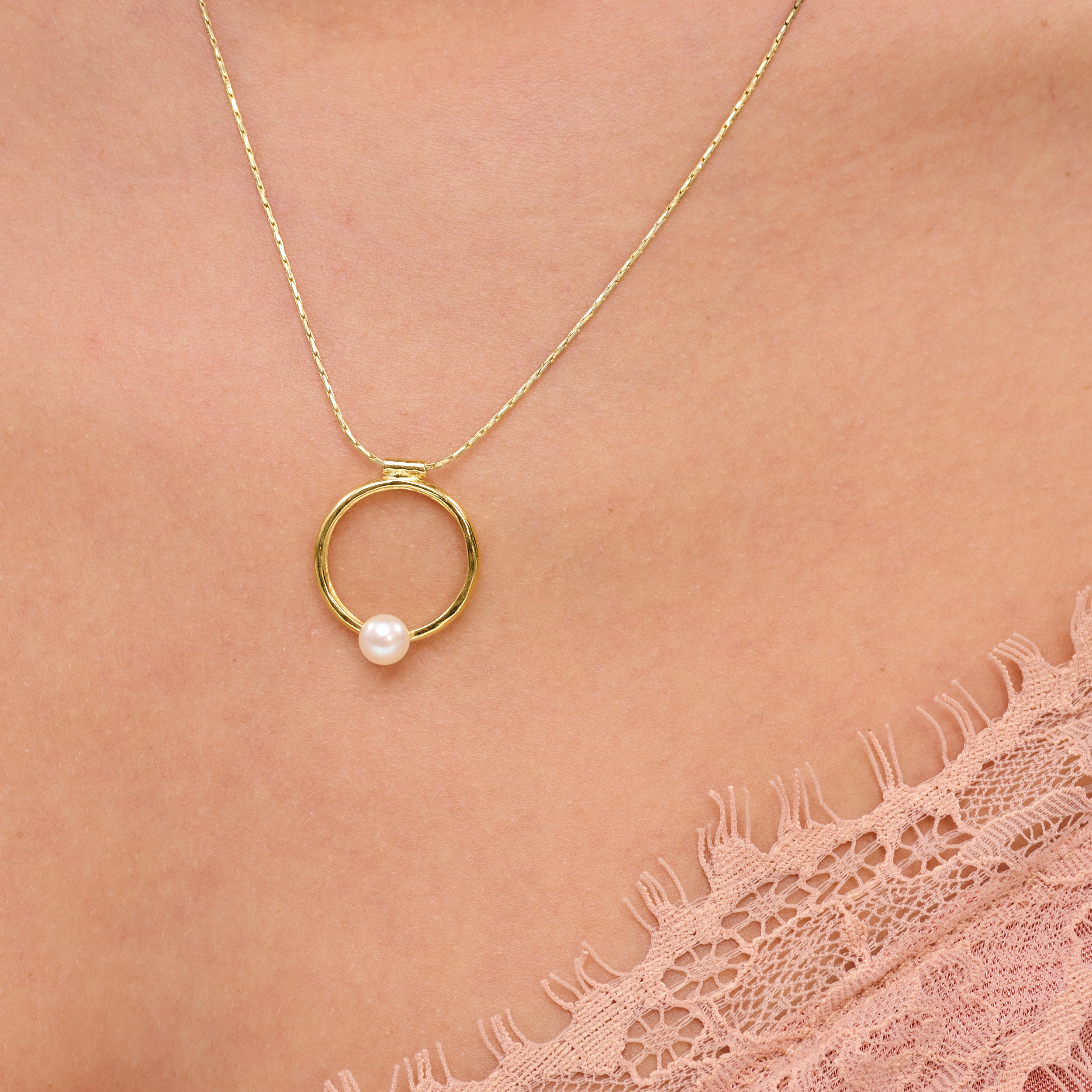 שרשרת בעיצוב אלגנטי עם תליון מוזהב בגודל דומיננטי, המשובץ בפנינת שמנת מעודנת – תכשיט קלאסי בעל נוכחות בולטת. הפנינה ממוקמת במרכז התליון ומקרינה אור רך וטבעי, תוך יצירת ניגוד מחמיא עם הציפוי הזהוב. עיצוב השרשרת משלב בין איזון בין רכות יוקרתית לאופנה עדכנית, ומתאים לאירועים חגיגיים כמו גם ללבוש יומיומי עם נגיעה נשית. פנינים ידועות כמזוהות עם סטייל נשי טהור – ויחד עם הזהב, נוצרת הרמוניה מושלמת בין אלגנטיות לחמימות.