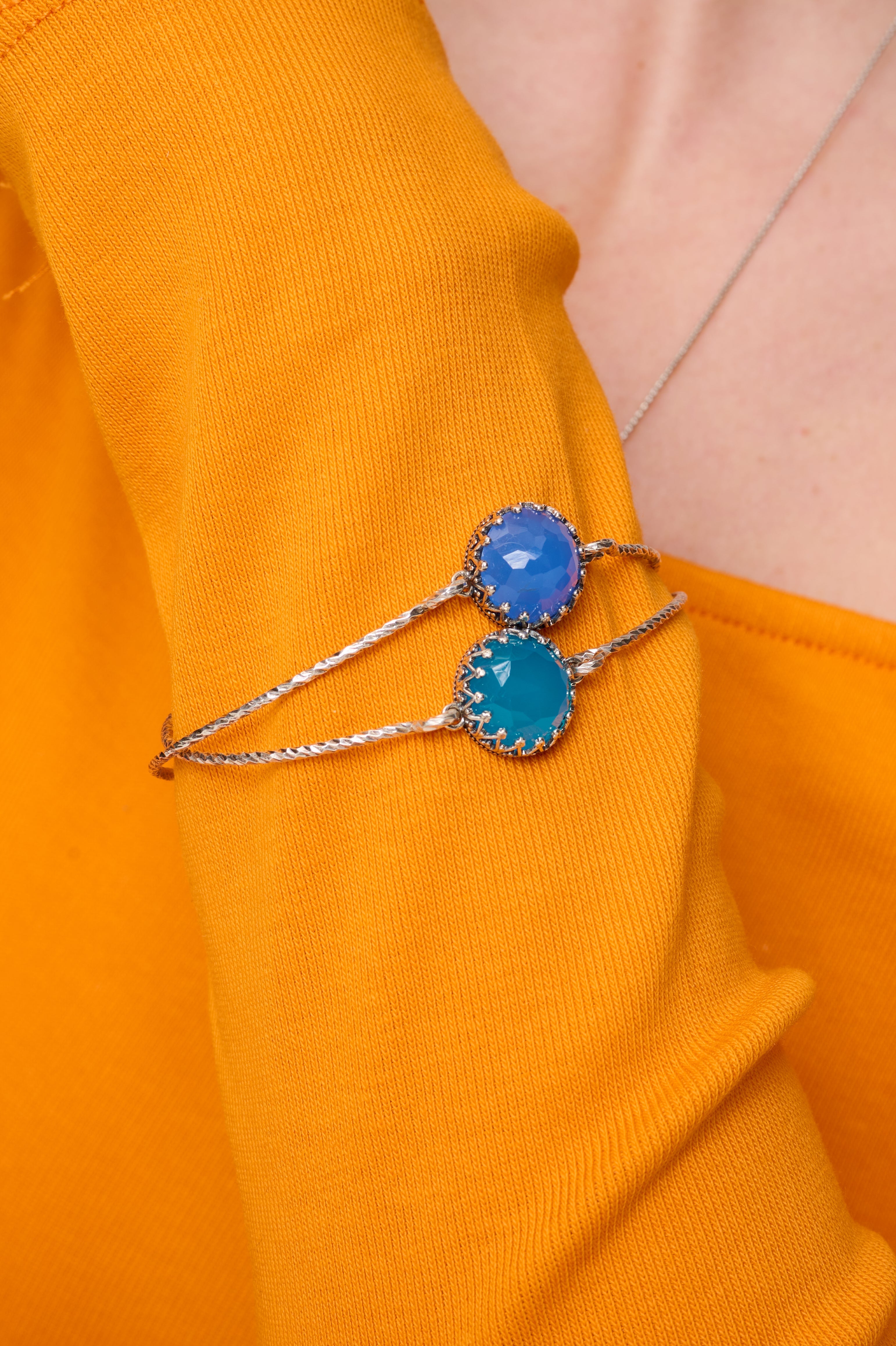 תכשיט קלאסי עם נגיעה מודרנית – צמיד כסף קשיח עם שיבוץ של אופלית כחולה בעלת אפקט זוהר ופנינה. הצבע הכחול העמוק עם נצנוץ פנימי מוסיף מימד של מסתורין ותחכום. הצמיד מתאים לנשים שאוהבות לשלב בין פשטות לעוצמה שקטה. נוח לענידה, עם גימור איכותי ונוכחות אלגנטית שלא נעלמת. מושלם כמתנה לאישה מלאת השראה וחלומות.

צמיד שני להמחשה בלבד