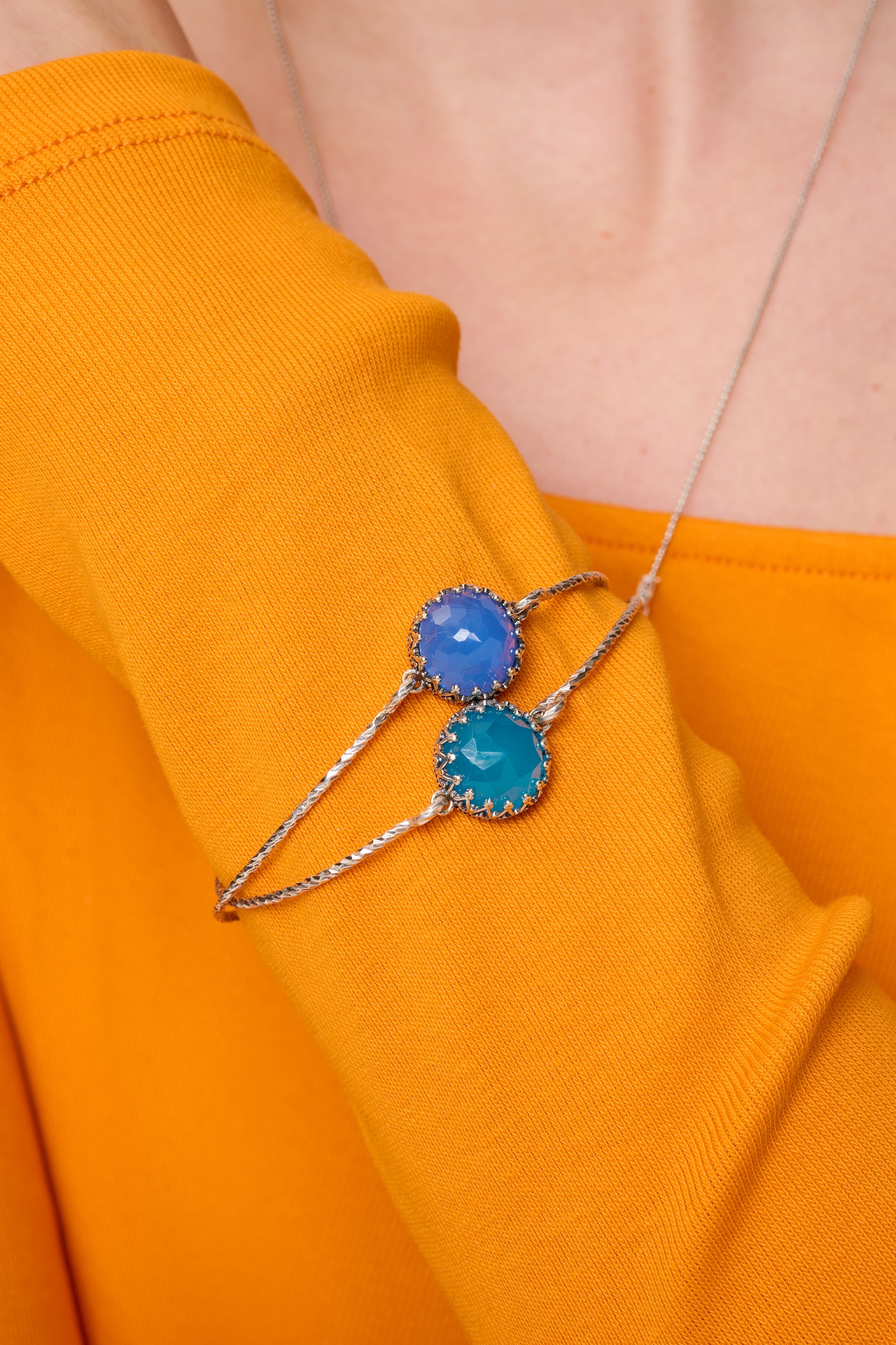 צמיד כסף בעיצוב מינימליסטי ועדין, עם שיבוץ של אופלית כחולה בגימור מלוטש. האבן משדרת גוונים משתנים של כחול, טורקיז וסגול לפי האור, מה שמעניק לתכשיט חיות וקסם אישי. הצמיד קשיח ונוח לענידה, מתאים לנשים שמעריכות עיצוב איכותי, אבן עם אופי וסגנון אישי. מתנה מושלמת לאישה יצירתית, רגישה ומלאת השראה.

צמיד השני להמחשה בלבד