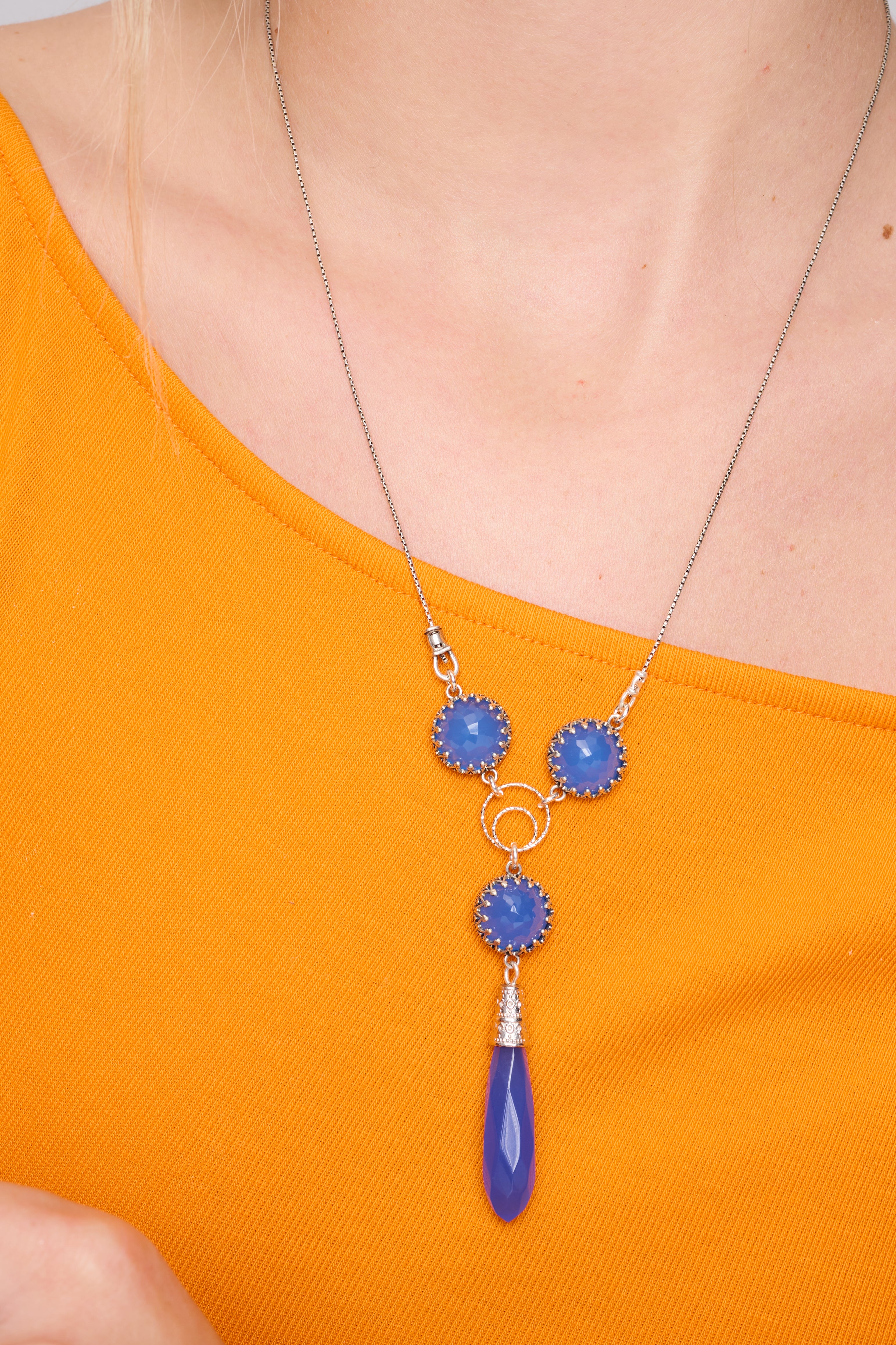 שרשרת כסף אלגנטית עם תליון מעוצב בעבודת יד, המשובץ באופלייט כחול בגוון שמזכיר ים שקט תחת אור ירח. האבן משדרת זוהר פנימי רך עם אפקט פנינתי שמשתנה לפי התאורה. שילוב מושלם של מתכת קרירה עם אבן מוארת – מראה עדין, הרמוני ומלא רוך.

