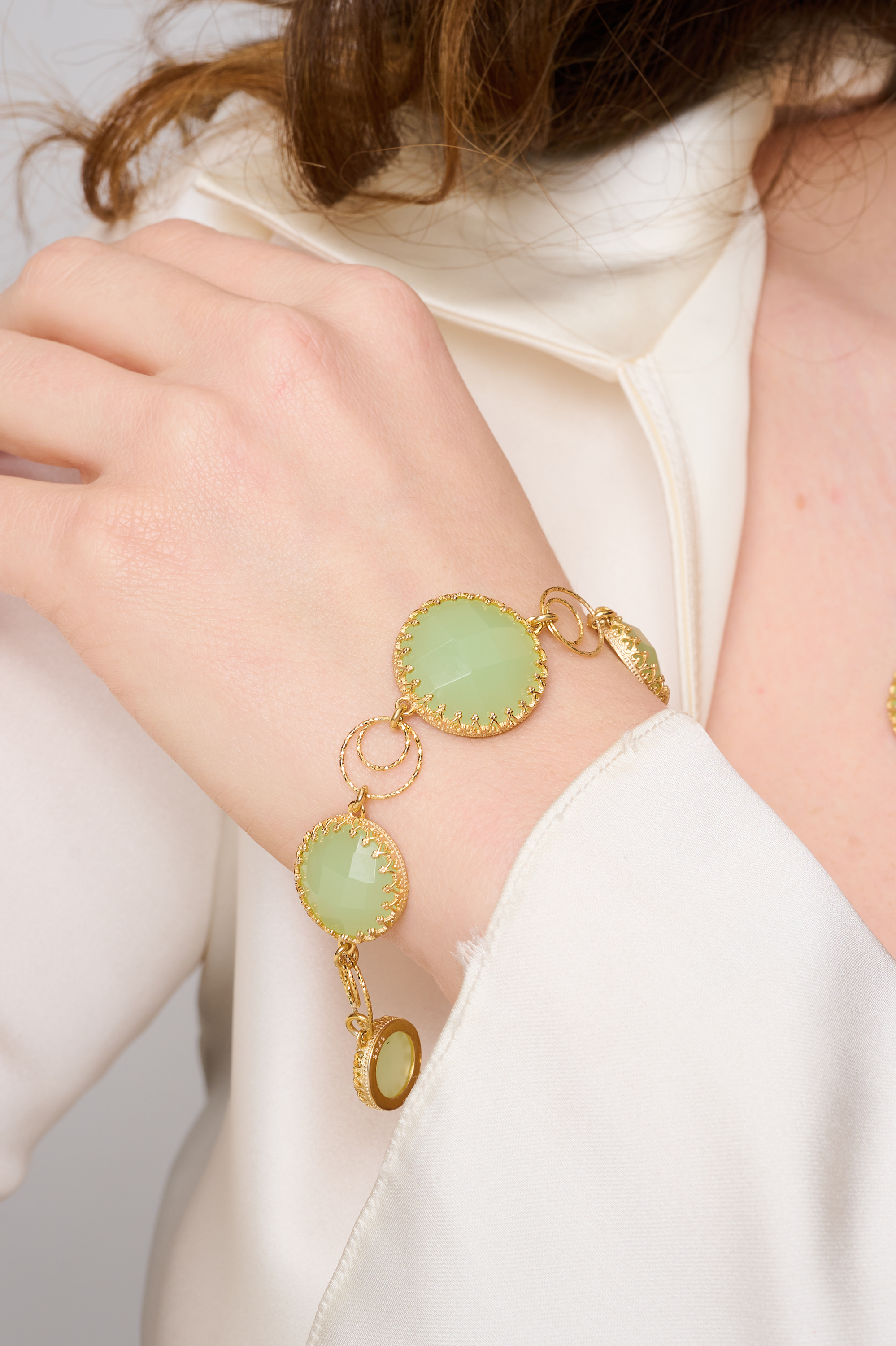 צמיד כסף מצופה זהב בעיצוב קלאסי ועדין, משובץ באבני אופליט ירוקות בגוון פסטלי מרגיע עם ברק חלבי רך. כל אבן עגולה משובצת במסגרת זהובה בסגנון תחרה, והחוליות העגולות בין האבנים מוסיפות תחושת קלילות ותנועה. תכשיט בעבודת יד שמביא איתו איזון, שלווה ונשיות רכה. מתאים לנשים שאוהבות מראה טבעי עם נגיעה יוקרתית – מושלם לערב, אירועים חגיגיים או כמתנה עם משמעות.

