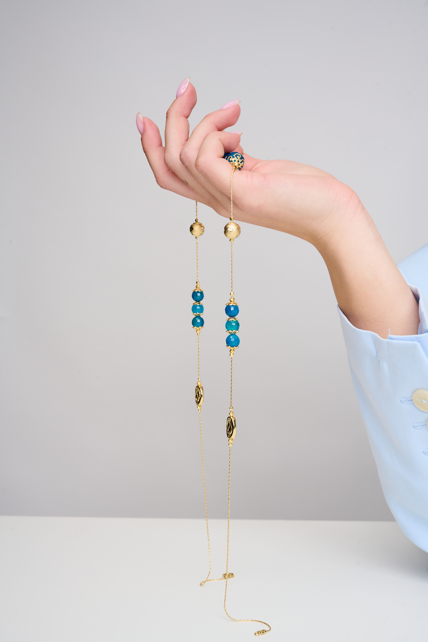 שרשרת עבודת יד מאבני כריסוקולה טבעיות בגווני טורקיז, ירוק וכחול עמוק – מפגש הרמוני בין גווני טבע עזים. כל אבן נבחרת בקפידה ומציגה דפוס ייחודי משלה, אין שתיים זהות – כל תכשיט מספר סיפור אחר. הכריסוקולה ידועה כאבן עם אנרגיה טבעית של שלווה והרמוניה, כזו שמחברת את הלובשת לאנרגיה פנימית של שקט וביטחון. העיצוב של השרשרת שומר על קו נקי ומוקפד, ומבליט את יופיין הגולמי של האבנים. מתאים למי שמחפשת עיצוב שכולו טבע, רגש ואיזון.