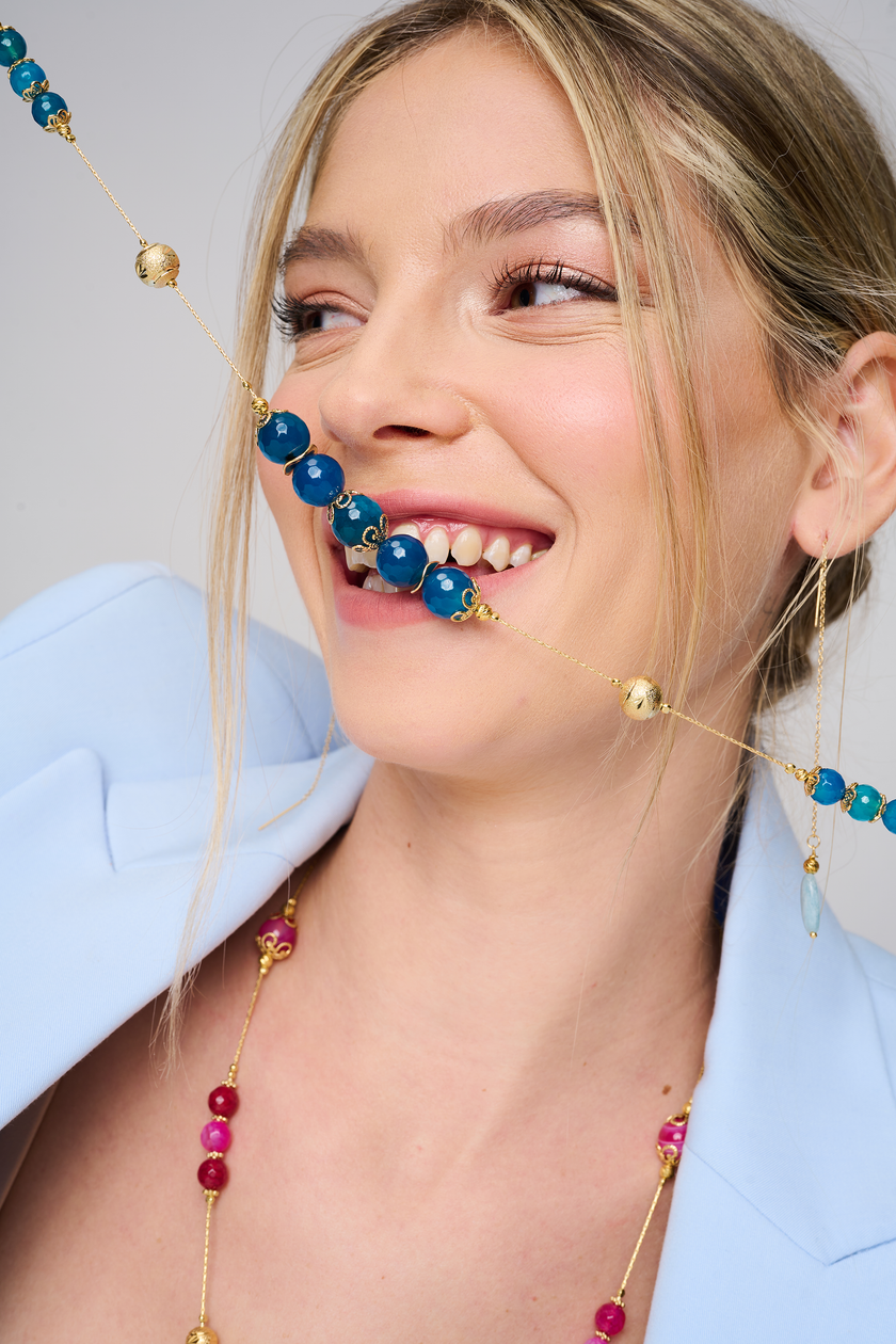 שרשרת ארוכה בעבודת יד מאבני אגט כחולות – עיצוב קלאסי בגווני מים ושקט. החרוזים משתנים בין תכלת בהיר לכחול עמוק, מה שיוצר מראה שמתאים לכל עונה וסגנון. העיצוב הארוך מאפשר גמישות – ניתן לענוד את השרשרת באורך מלא או לעטוף פעמיים למראה רב-שכבתי. אבן האגט נחשבת לאבן הגנה והרגעה, ומוסיפה מגע מרפא שמקרין איזון פנימי. תכשיט מושלם למי שמחפשת גם צבע, גם סגנון וגם תחושת חיבור רגשי לטבע.