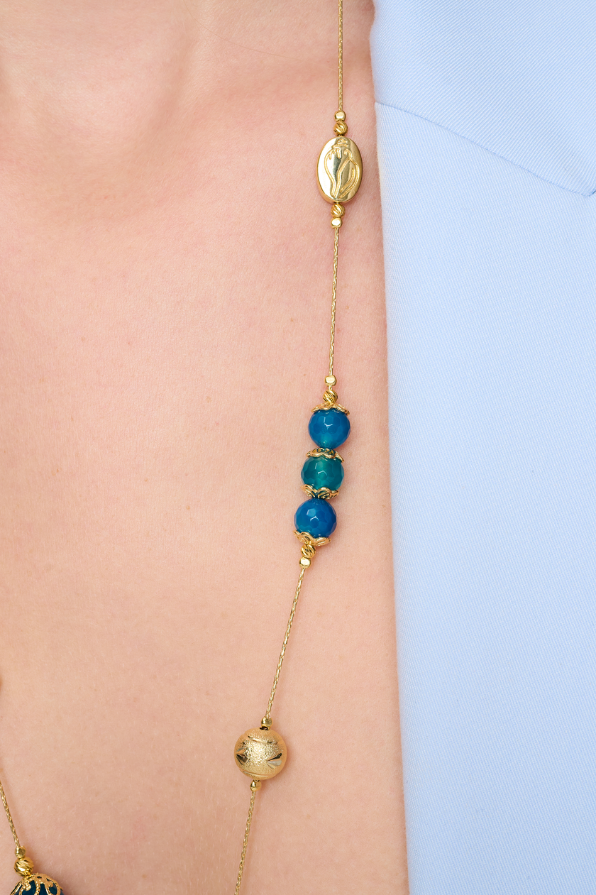 שרשרת ארוכה בעבודת יד מאבני אגט כחולות – מראה כחול עשיר שמקרין יציבות פנימית. החרוזים משתנים בין תכלת בהיר לכחול עמוק, מה שיוצר רכות צבעונית שמרגיעה את המבט. העיצוב הארוך מאפשר גמישות – ניתן לענוד את השרשרת באורך מלא או לעטוף פעמיים למראה רב-שכבתי. אבן האגט נחשבת לאבן הגנה והרגעה, ומוסיפה מגע מרפא שמקרין איזון פנימי. תכשיט מושלם למי שמחפשת גם צבע, גם סגנון וגם תחושת חיבור רגשי לטבע.