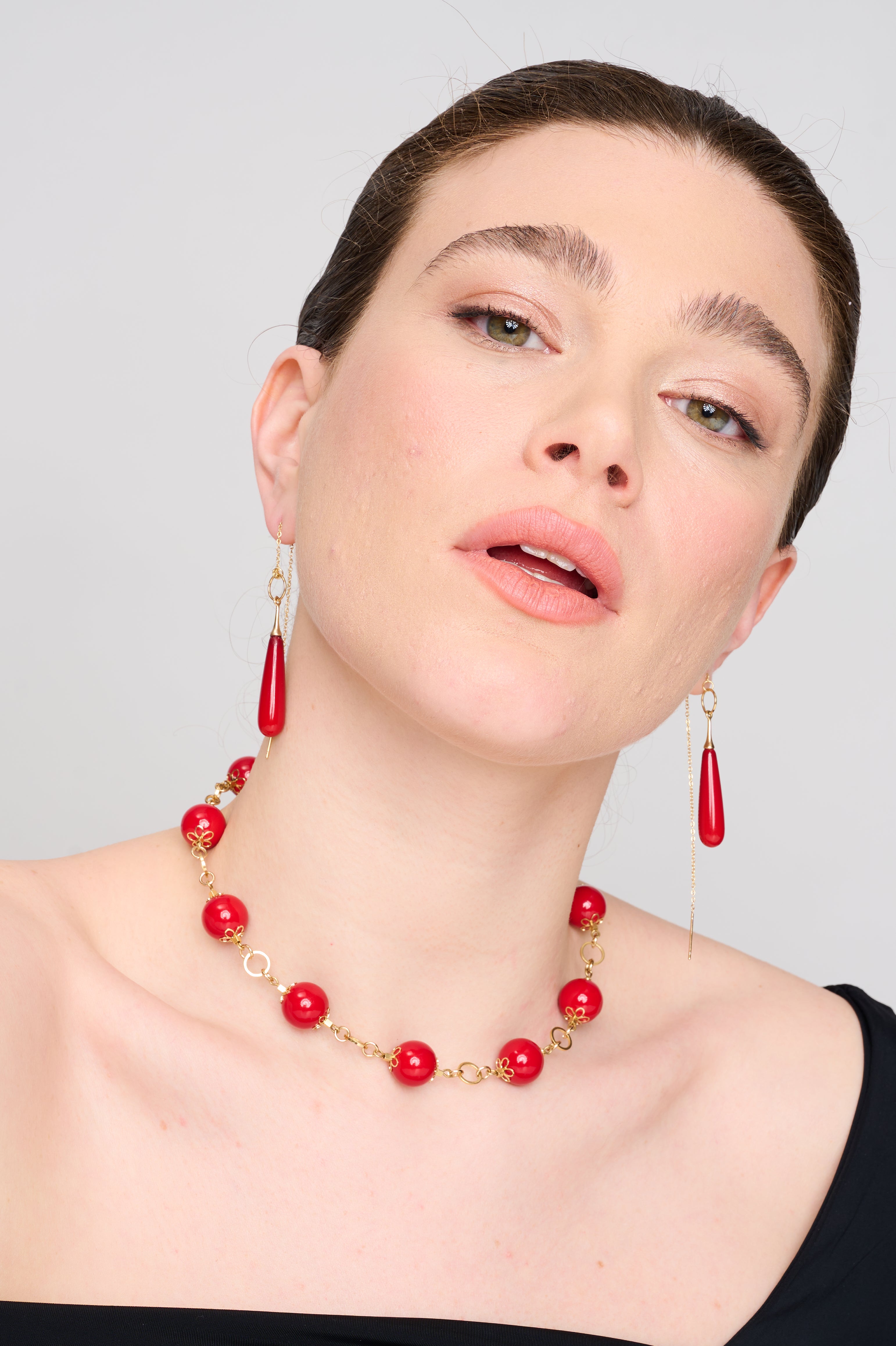 תכשיט מעוצב בעבודת יד: חרוזים עגולים בצבע אדום עז, עשויים חומר מבריק, שזורים בסוגריים מוזהבים מעוטרים בצורת פרח. השרשרת משדרת שילוב בין קלאסיקה לרעננות עכשווית, על רקע כהה שמבליט את הניגוד בין הצבעים ויוצר אפקט חזותי מרשים.
המחיר מתייחב לשרשרת בלבד