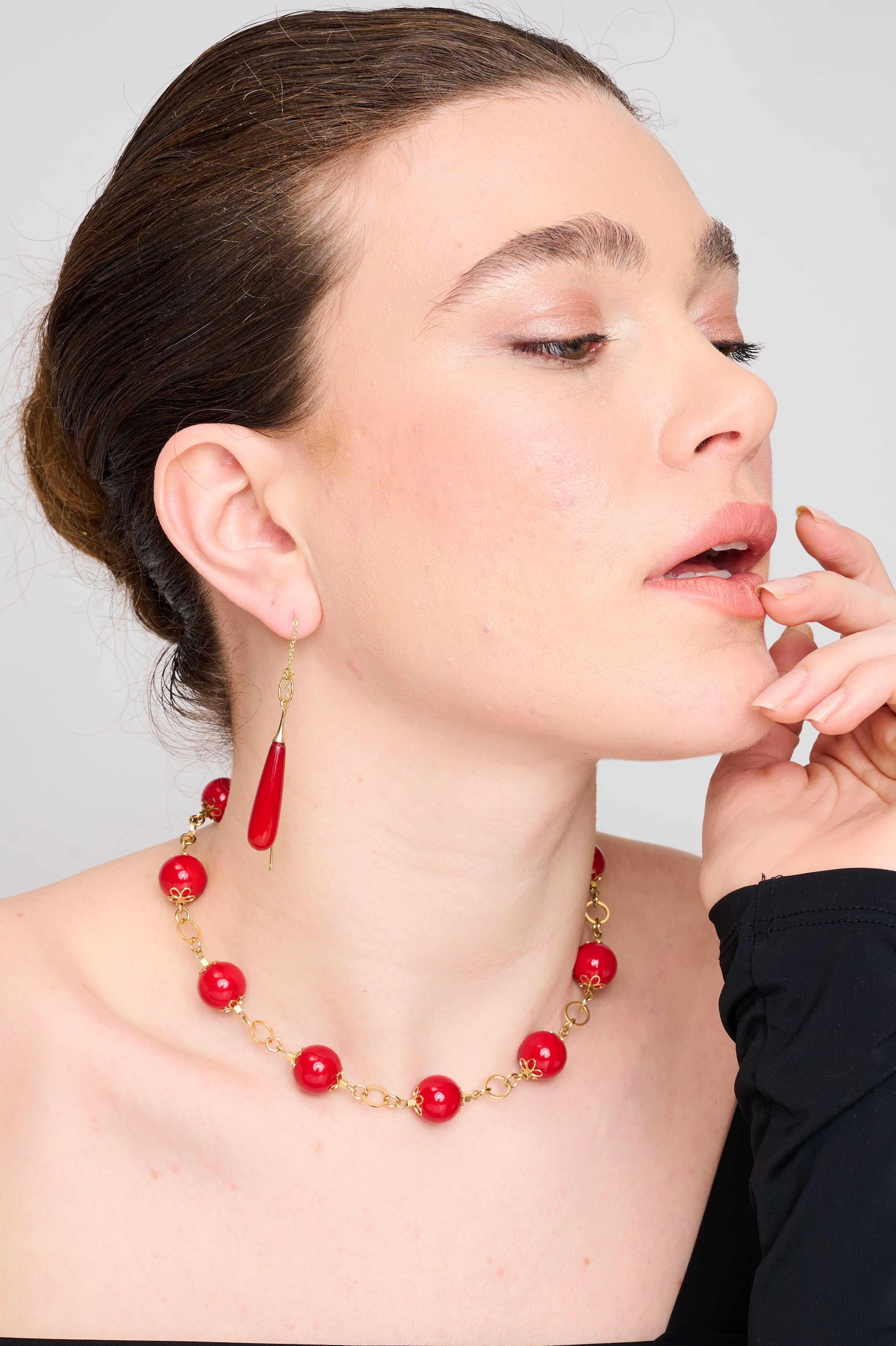 שרשרת עוצמתית בסגנון רטרו-גלאם, המורכבת מחרוזים אדומים גדולים מבריקים שמחוברים בסוגריים פרחוניים מוזהבים. עיצוב עשיר בגוונים חמים ובניגודיות מרהיבה בין האדום לכתרים המוזהבים. מתאימה למראה ערב נוצץ או להשלמת לוק דרמטי.
העגילים להמחשה בלבד
