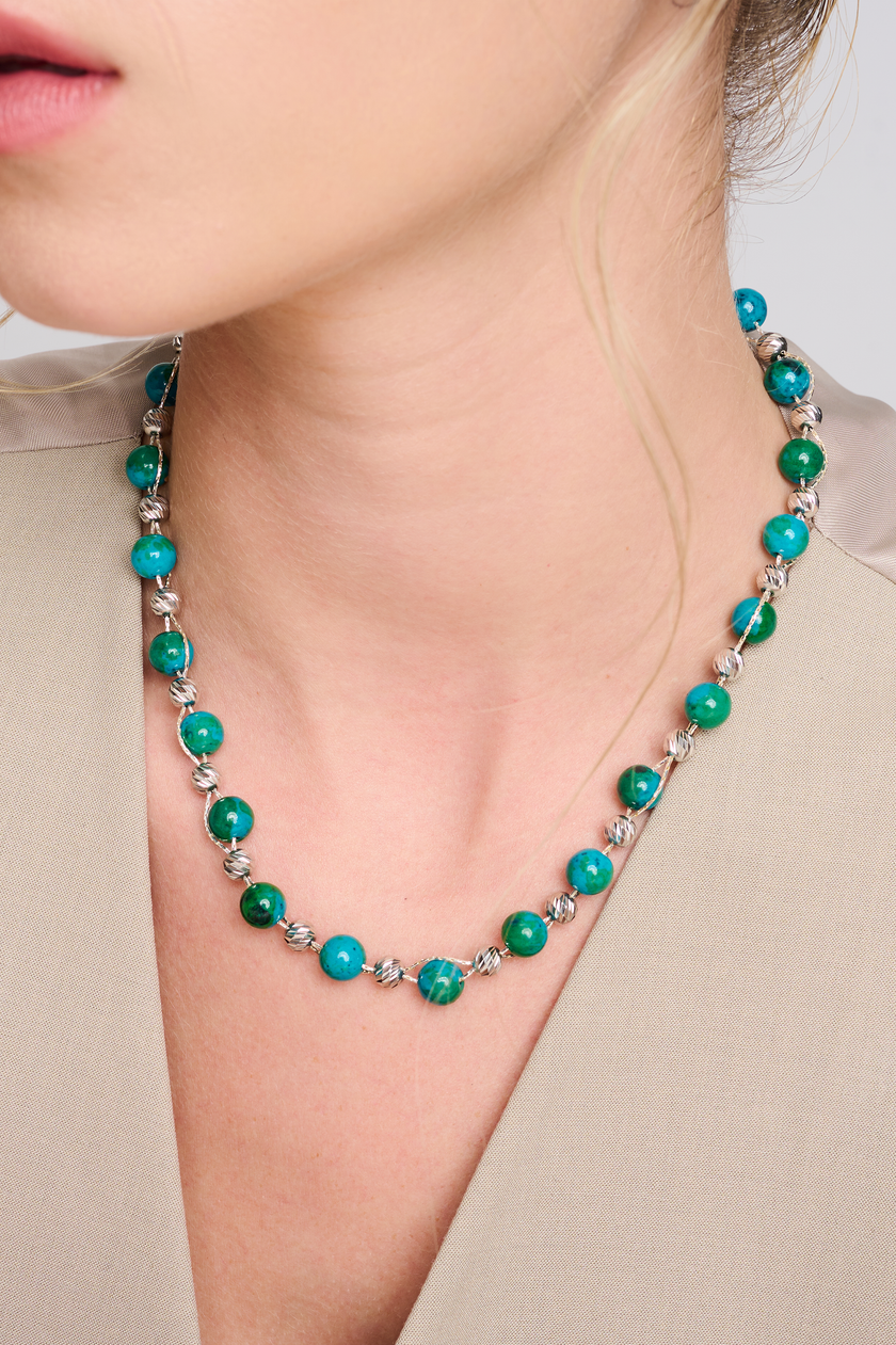 שרשרת עבודת יד מאבני כריסוקולה טבעיות בגווני טורקיז, ירוק וכחול עמוק – מפגש הרמוני בין גווני טבע עזים. כל אבן נבחרת בקפידה ומציגה דפוס ייחודי משלה, לכל שרשרת נוכחות משלה. הכריסוקולה ידועה כאבן עם אנרגיה טבעית של שלווה והרמוניה, כזו שמחברת את הלובשת לאנרגיה פנימית של שקט וביטחון. העיצוב של השרשרת שומר על קו נקי ומוקפד, ומבליט את יופיין הגולמי של האבנים. מתאים למי שמחפשת סטייל אישי עם נשמה.