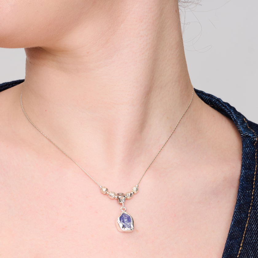 שרשרת כסף דקה עם תליון מרכזי עגול, משובץ באבן כחולה עדינה בעלת ברק שקוף וגוונים מתחלפים בין תכלת לכחול אפור. במרכז השרשרת מסודרים חרוזים כסופים במראה מלוטש ואחיד, היוצרים תחושת איזון וסימטריה. האבן משובצת במסגרת מתכת חלקה, בעלת קווים רכים ועגולים. תכשיט שמשדר ניקיון, שלווה ואסתטיקה על-זמנית. מתאים לנשים שמעריכות עיצוב מינימליסטי עם נגיעה צבעונית טבעית.

