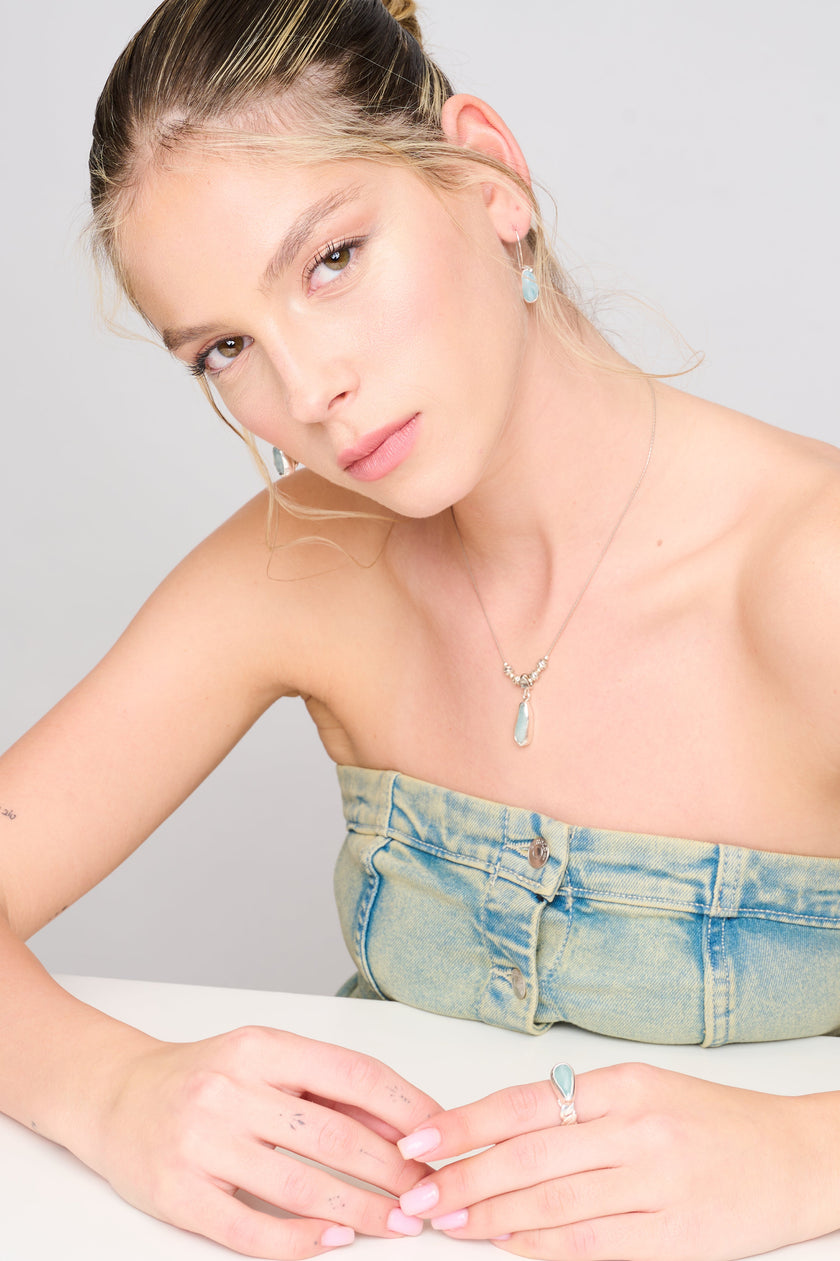 תליון א-סימטרי מכסף עם אבן בגוון תכלת טבעי משתלב בשרשרת דקה ועדינה, המעוטרת בחרוזים עגולים בעבודת יד. עיצוב מודרני בעל השראה אורגנית, אשר יוצר תחושת זרימה והרמוניה. תכשיט מרשים ופשוט כאחד – מושלם למראה שכבות או כלוק בודד.