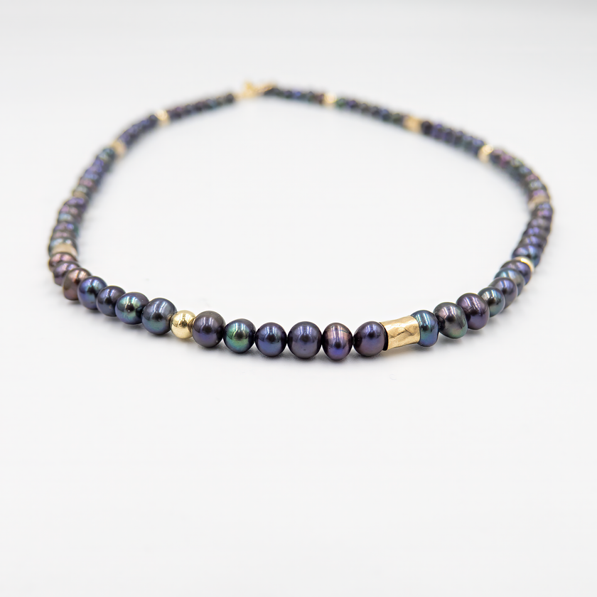 שרשרת צמודה עם פנינים שחורות ואלמנטים מוזהבים – קולר עם אמירה מסוגננת, שמשלב בין עומק אלגנטי לנגיעה חמימה של זהב. הפנינים השחורות יוצרות נוכחות דרמטית אך הרמונית, ואילו חרוזי הגולדפילד מוסיפים קונטרסט זוהר ושיק עכשווי. העיצוב הצמוד לצוואר מדגיש את קווי המתאר ומעניק מראה נשי, חזק ומתוחכם. תכשיט למראה חגיגי או כטאץ’ מדויק ביומיום.