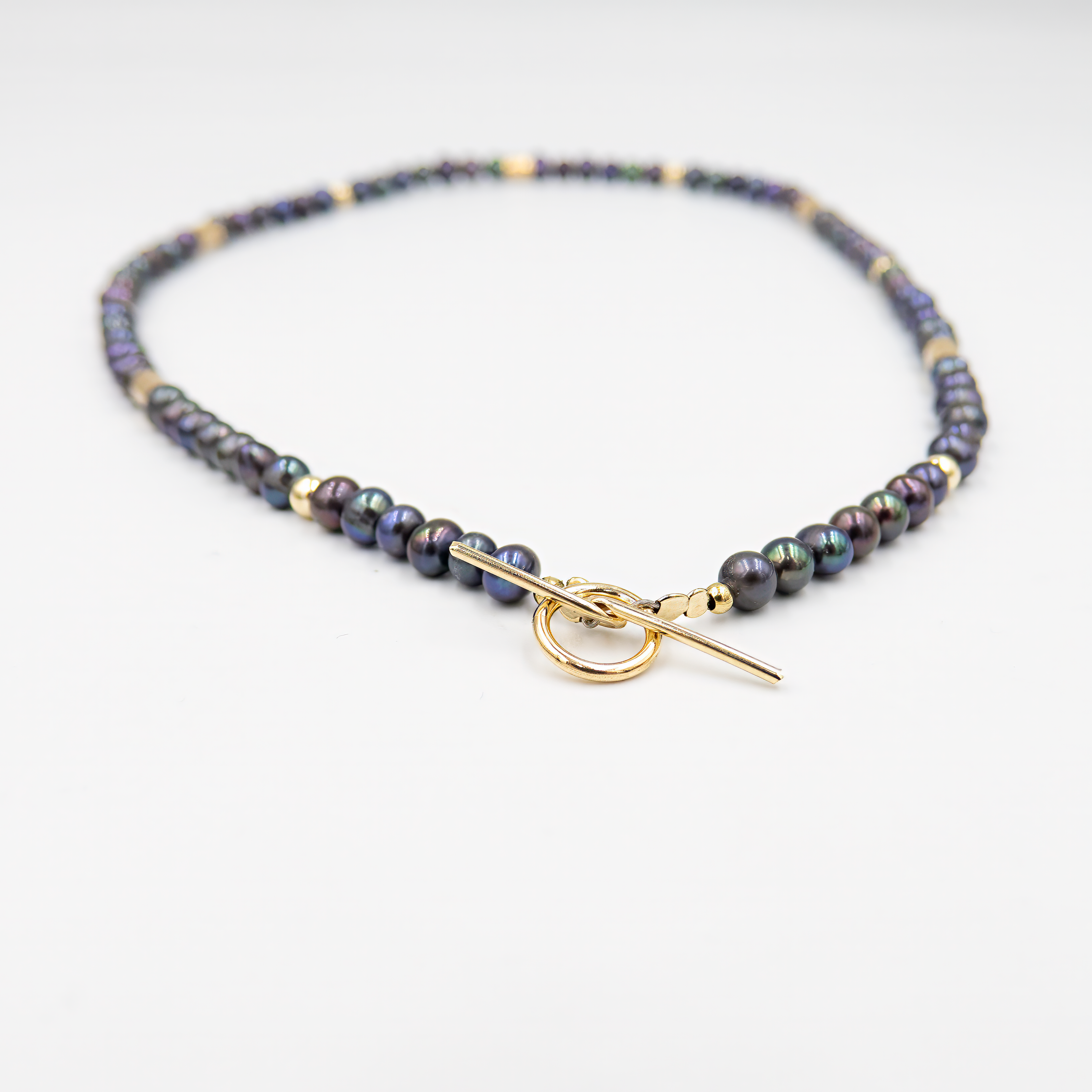 שרשרת צמודה עם פנינים שחורות ואלמנטים מוזהבים – קולר עם אמירה מסוגננת, שמשלב בין עומק אלגנטי לנגיעה חמימה של זהב. הפנינים השחורות יוצרות נוכחות דרמטית אך הרמונית, ואילו חרוזי הגולדפילד מוסיפים קונטרסט זוהר ושיק עכשווי. העיצוב הצמוד לצוואר מדגיש את קווי המתאר ומעניק מראה נשי, חזק ומתוחכם. תכשיט למראה חגיגי או כטאץ’ מדויק ביומיום.