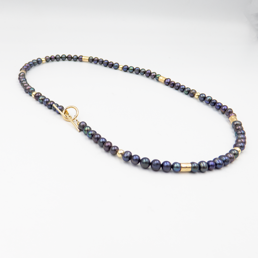 קולר אלגנטי עם פניני שחור וגולדפילד – קולר עם אמירה מסוגננת, שמשלב בין עומק אלגנטי לנגיעה חמימה של זהב. הפנינים השחורות יוצרות נוכחות דרמטית אך הרמונית, ואילו חרוזי הגולדפילד מוסיפים קונטרסט זוהר ושיק עכשווי. העיצוב הצמוד לצוואר מדגיש את קווי המתאר ומעניק מראה נשי, חזק ומתוחכם. תכשיט פריט ורסטילי שמשדר יוקרה ורוך.